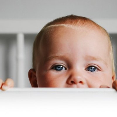 Baby peaking up from crib.